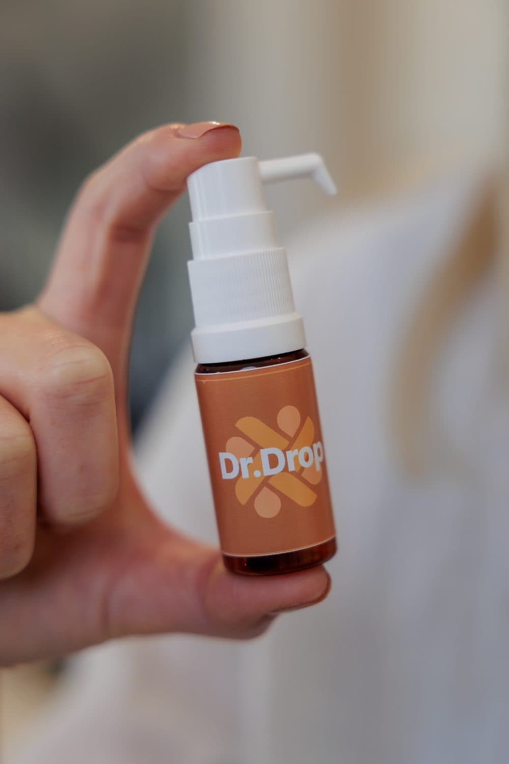 A hand holding the Dr.Drop allergy-drop bottle