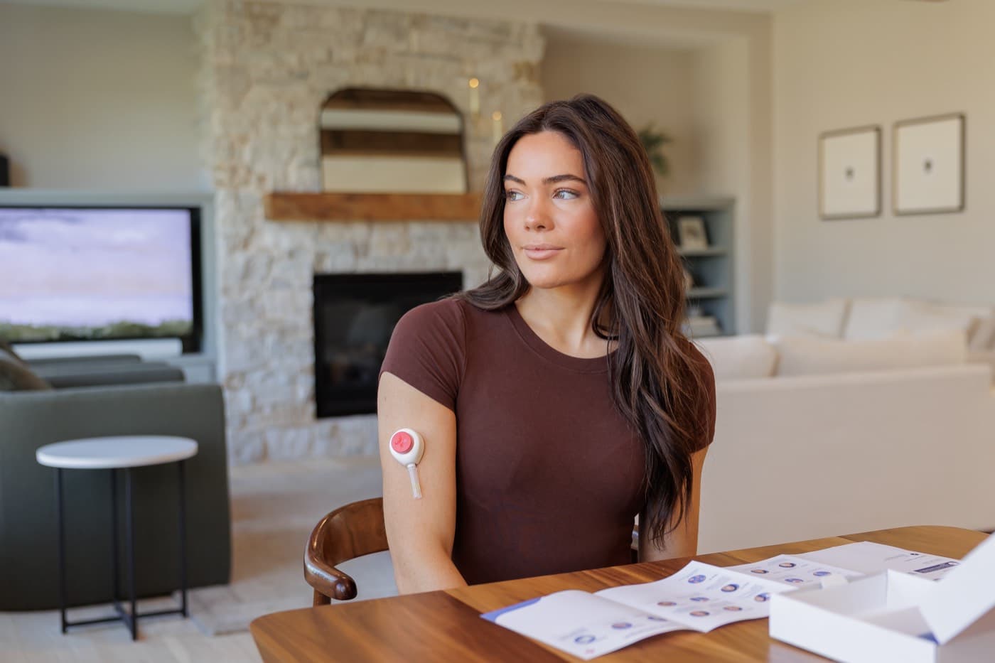 A woman using the painless collection device on her upper arm at home